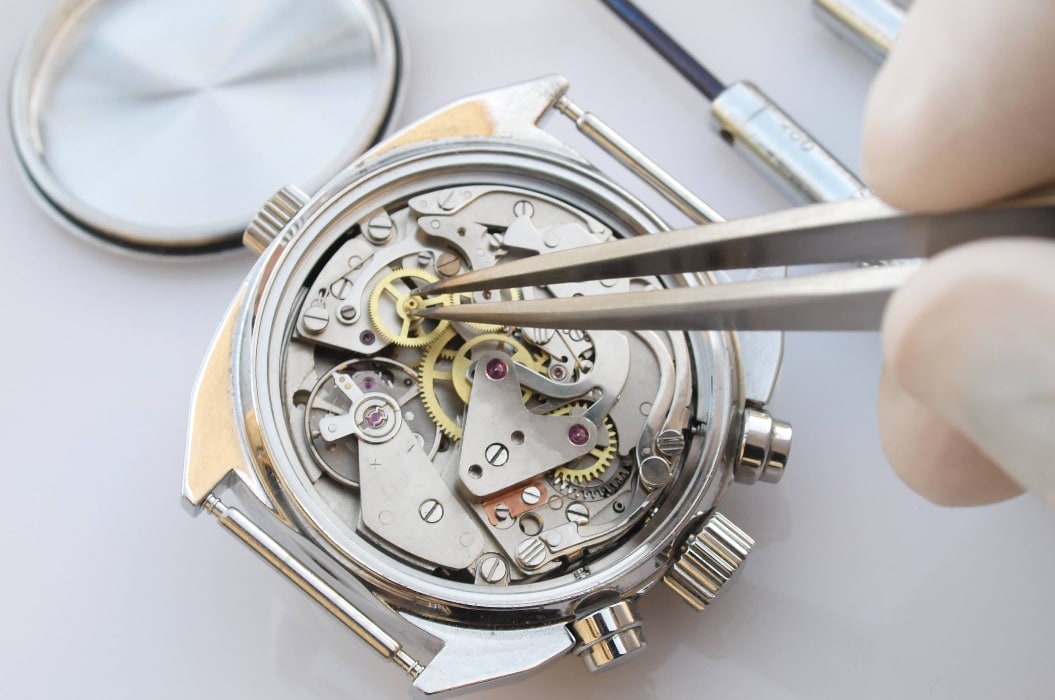 close up macro pic of vintage chronograph watch mechanism under repair by watchmaker